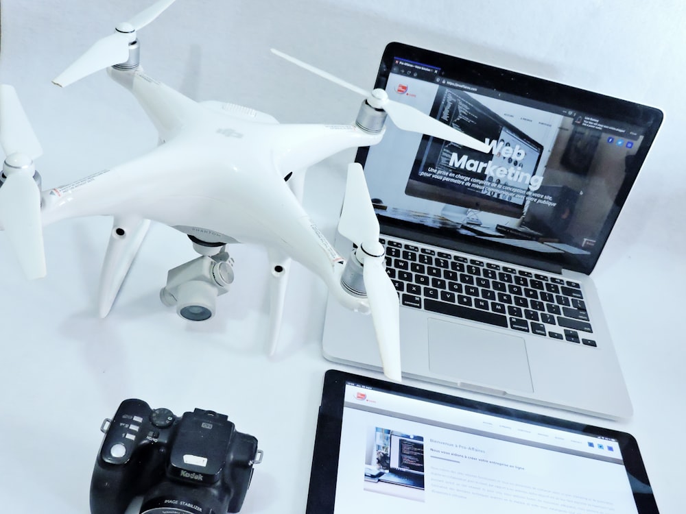 white and black drone near black and silver laptop computer