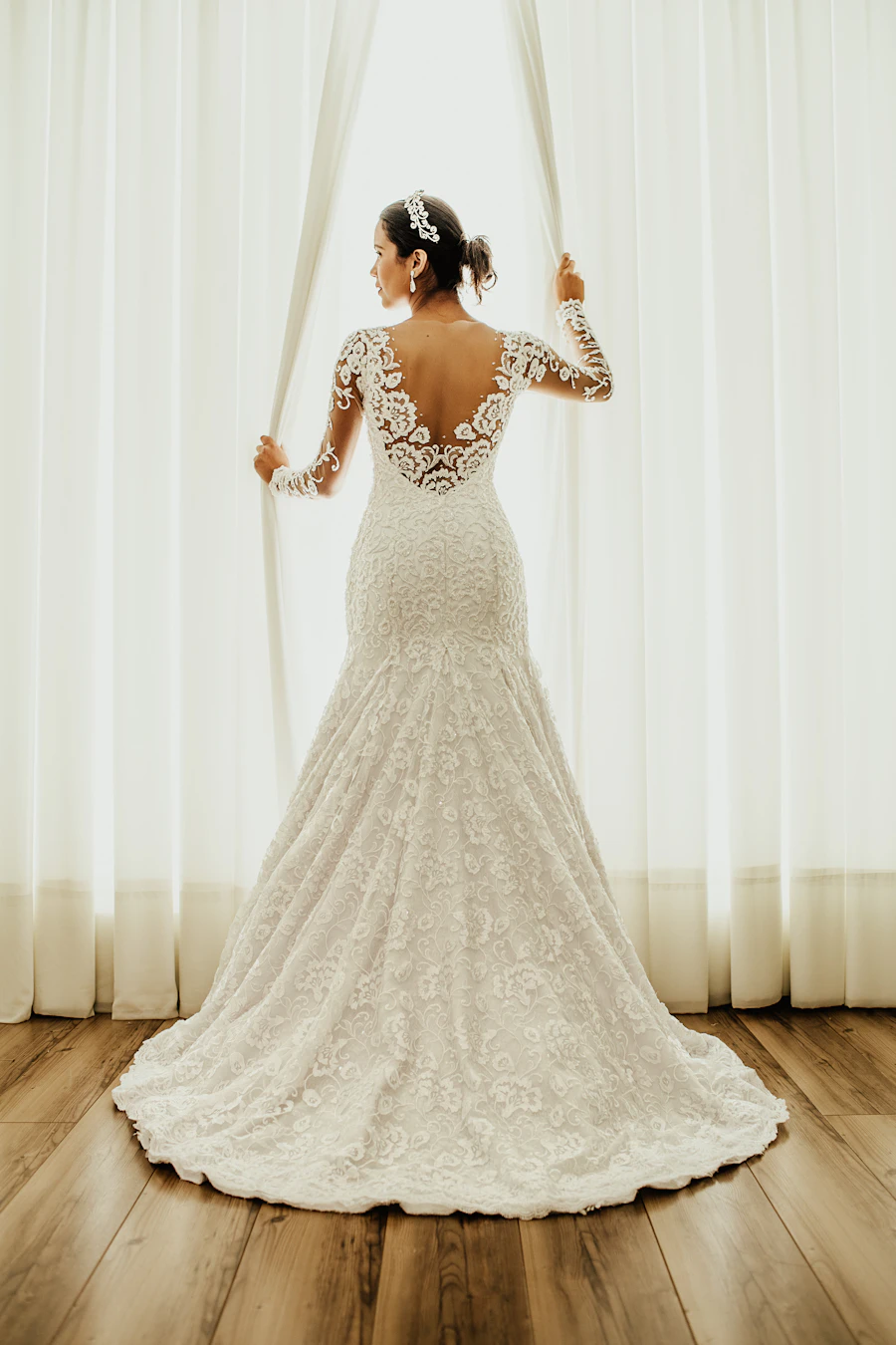 Back view of a fitted lace wedding gown with a long train