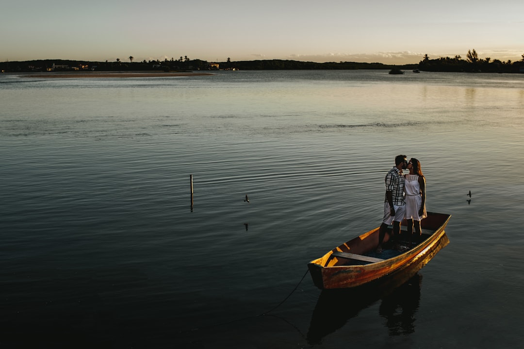 man in blue and white plaid dress shirt sitting on brown boat on sea during daytime