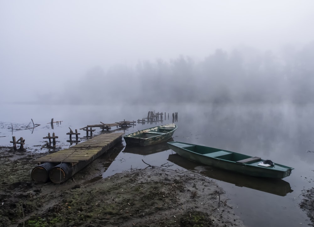 green and white boat on body of water during foggy weather