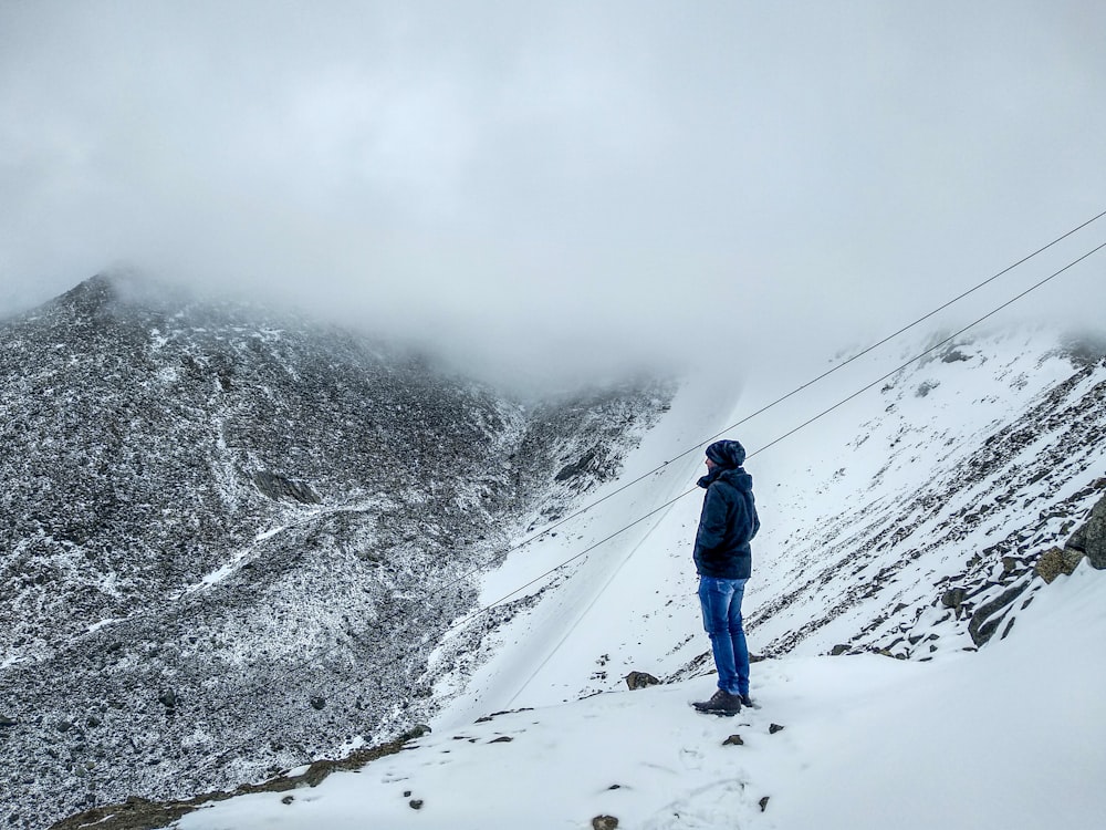 man in blue jacket and blue pants walking on snow covered ground