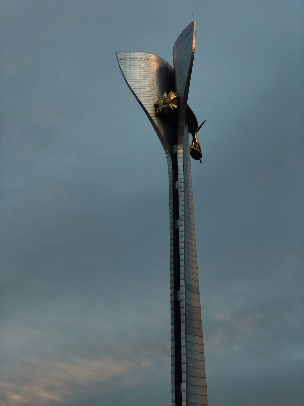 brown and black bird flying over the gray tower