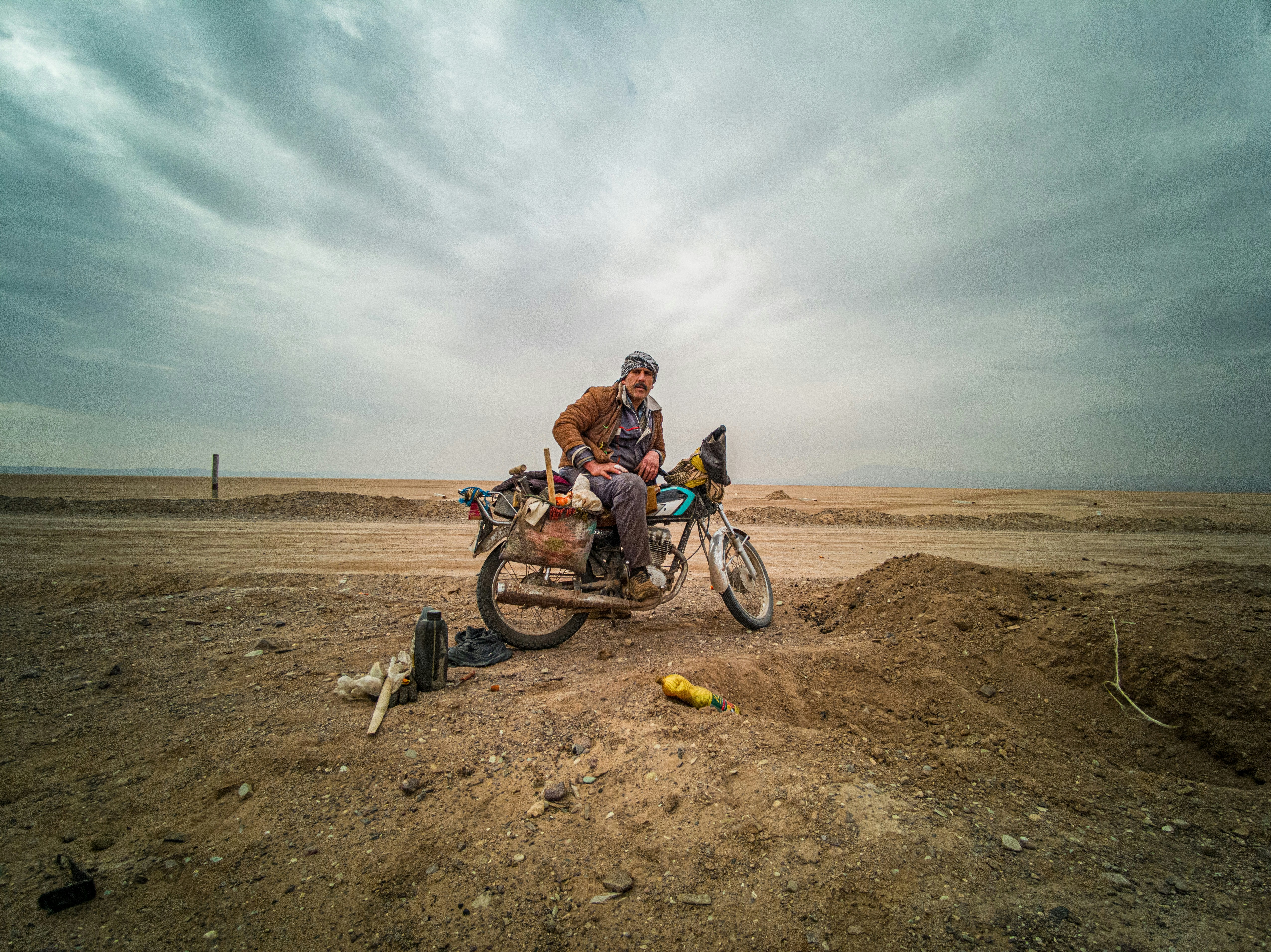 man in orange jacket riding on bicycle on brown sand during daytime
