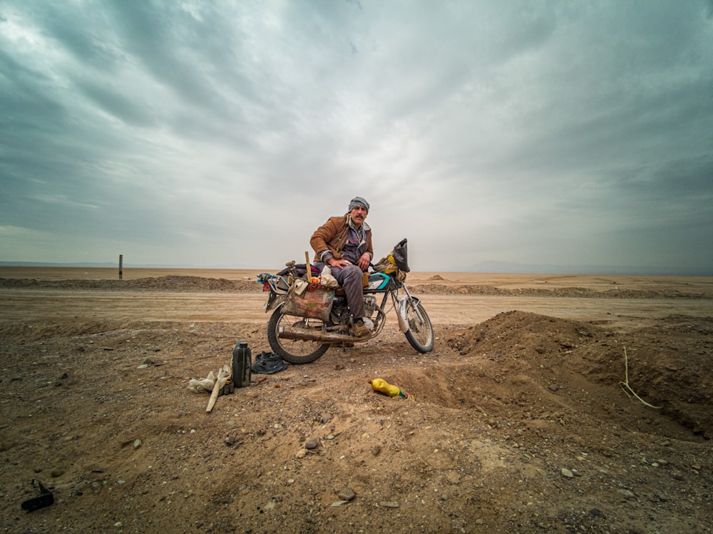 man in orange jacket riding on bicycle on brown sand during daytime