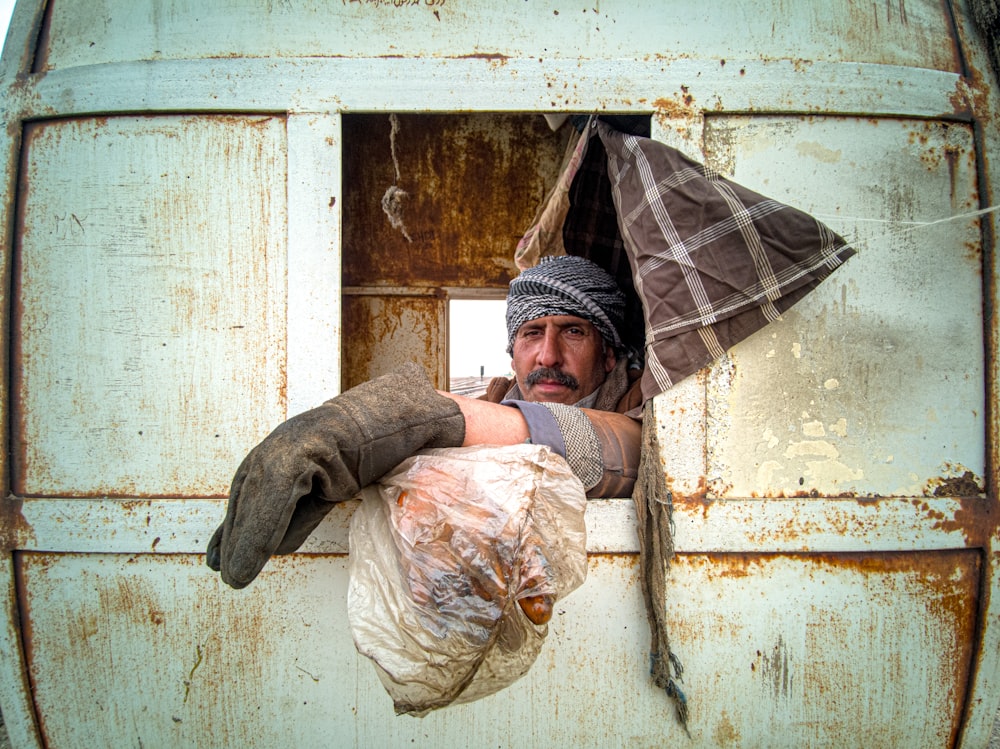 man in brown jacket and black hat holding umbrella