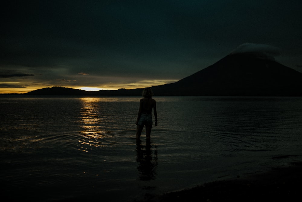 silhouette of man and woman standing on seashore during sunset