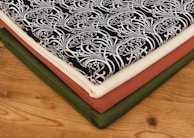 Stack of finished handwoven, handdyed, and embroidered fabrics ready for sale.