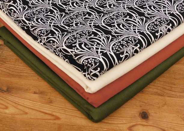 A neatly folded stack of black than cloths showcasing various shades and textures.