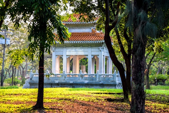 white concrete building near green trees during daytime in Lumphini Park Thailand