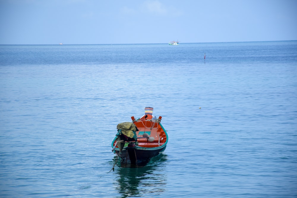 2 men riding on red boat on sea during daytime