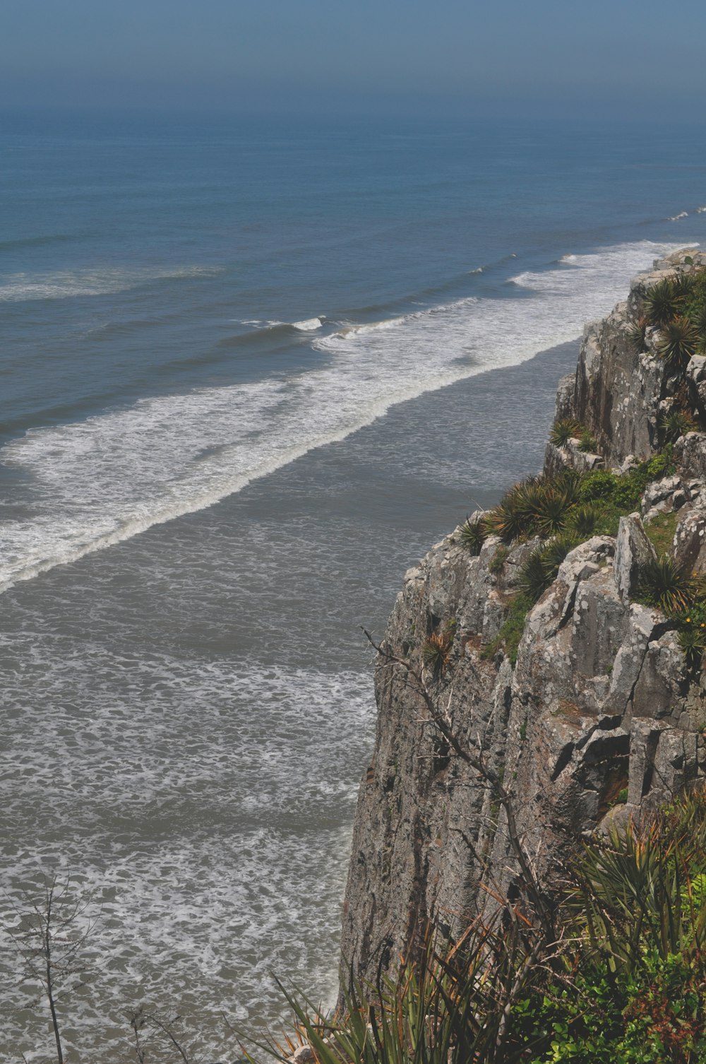 green and brown rock formation beside body of water during daytime