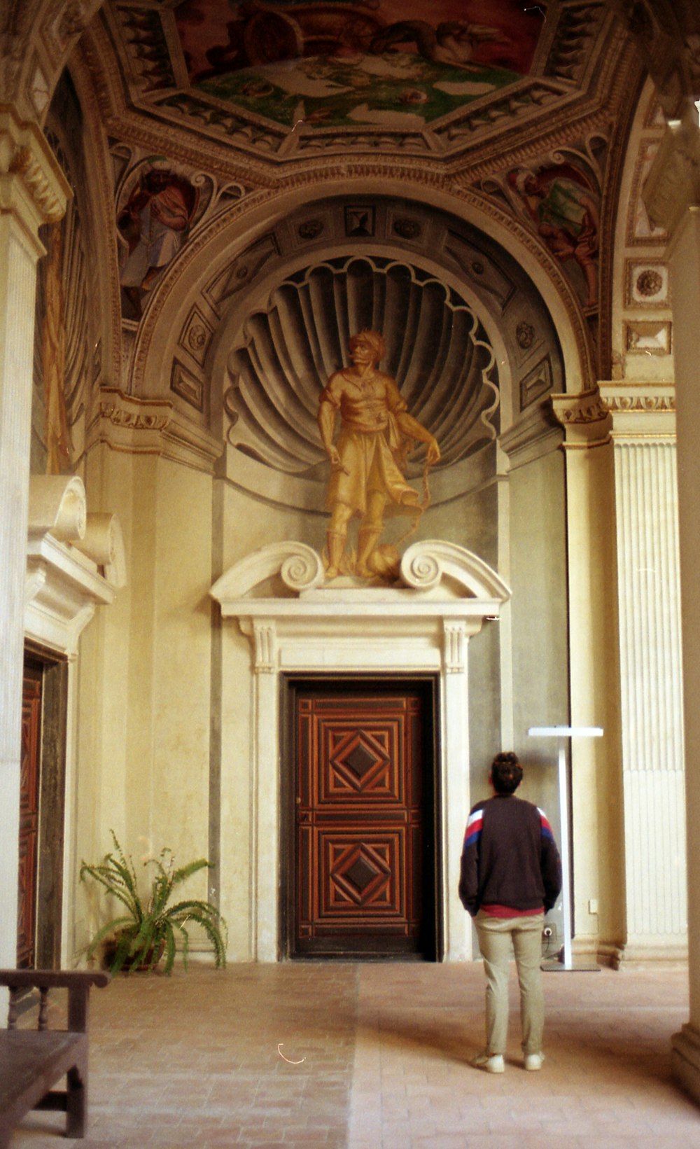 man in black jacket standing in front of brown wooden door