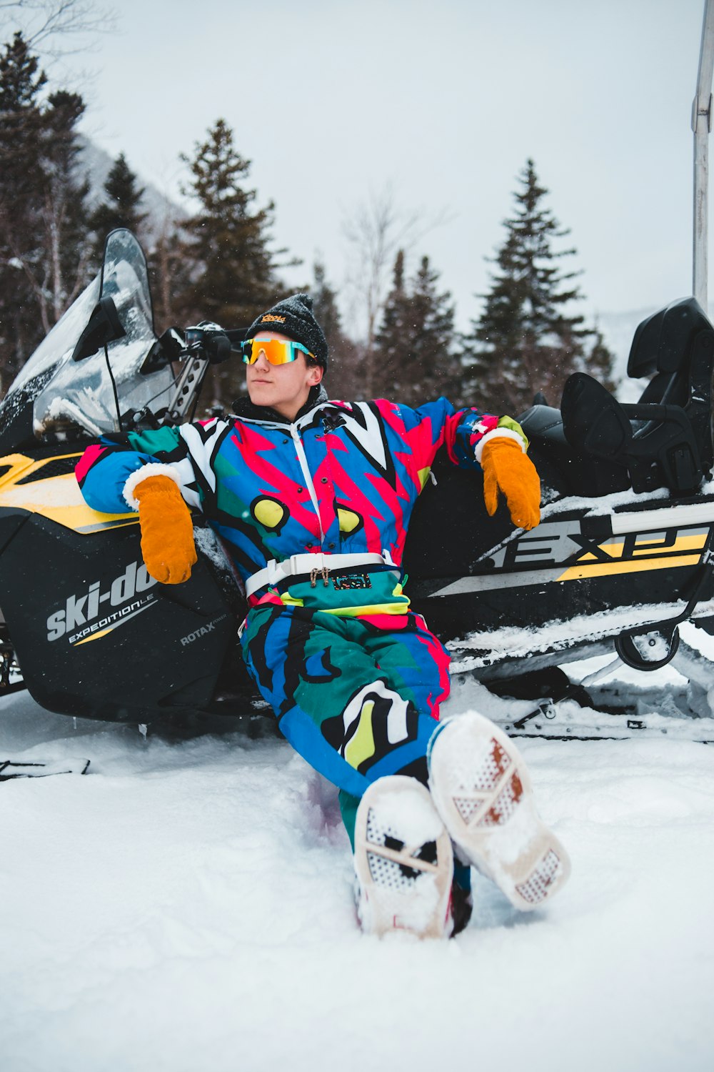 man in blue and yellow jacket riding on black and red snow sled