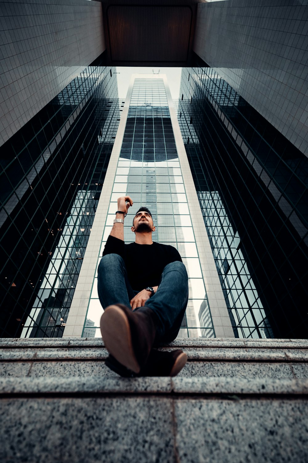 homem em jeans azul sentado nas escadas