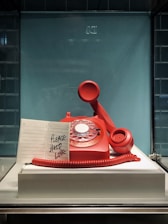 red and white rotary telephone on white table