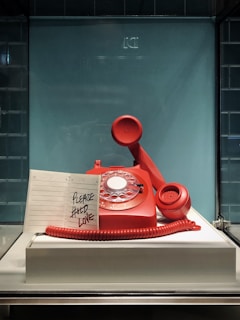 red and white rotary telephone on white table