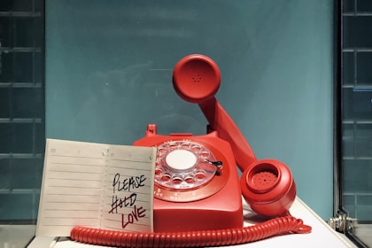 red and white rotary telephone on white table