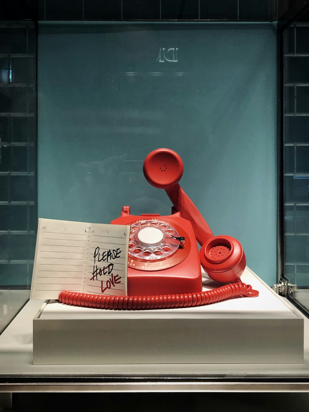 Teléfono de disco rojo y blanco sobre mesa blanca