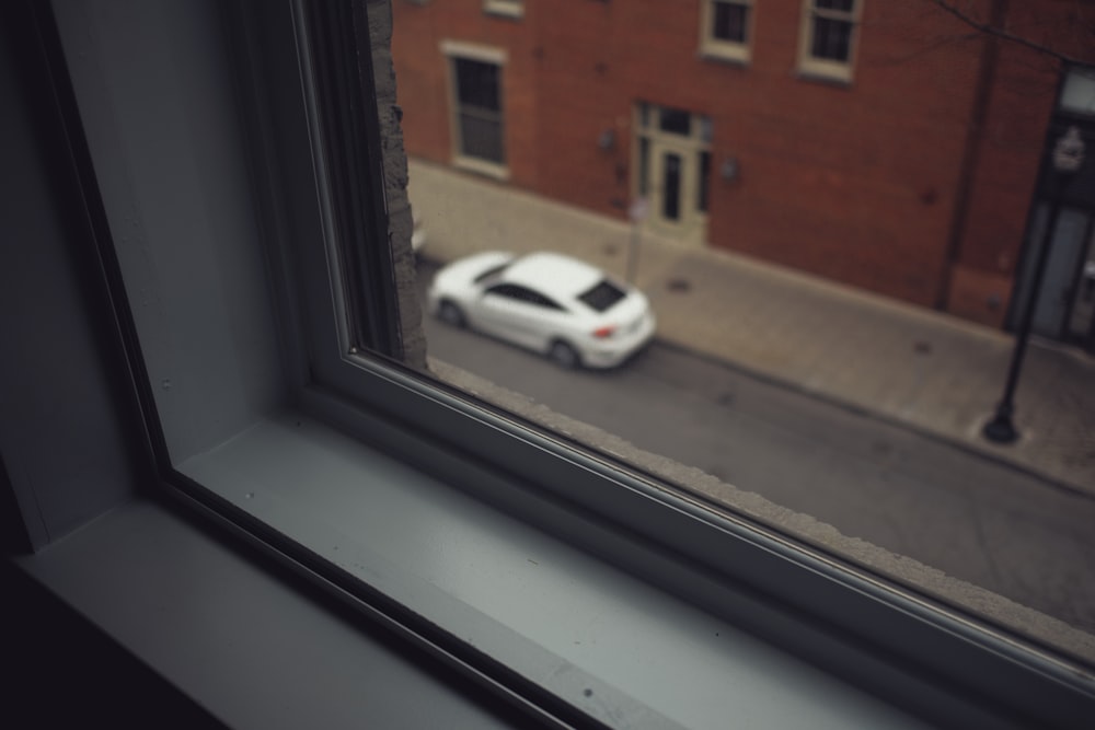 white car parked beside brown concrete building during daytime