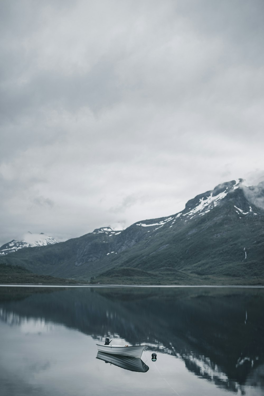 green and white mountains near lake under white clouds during daytime