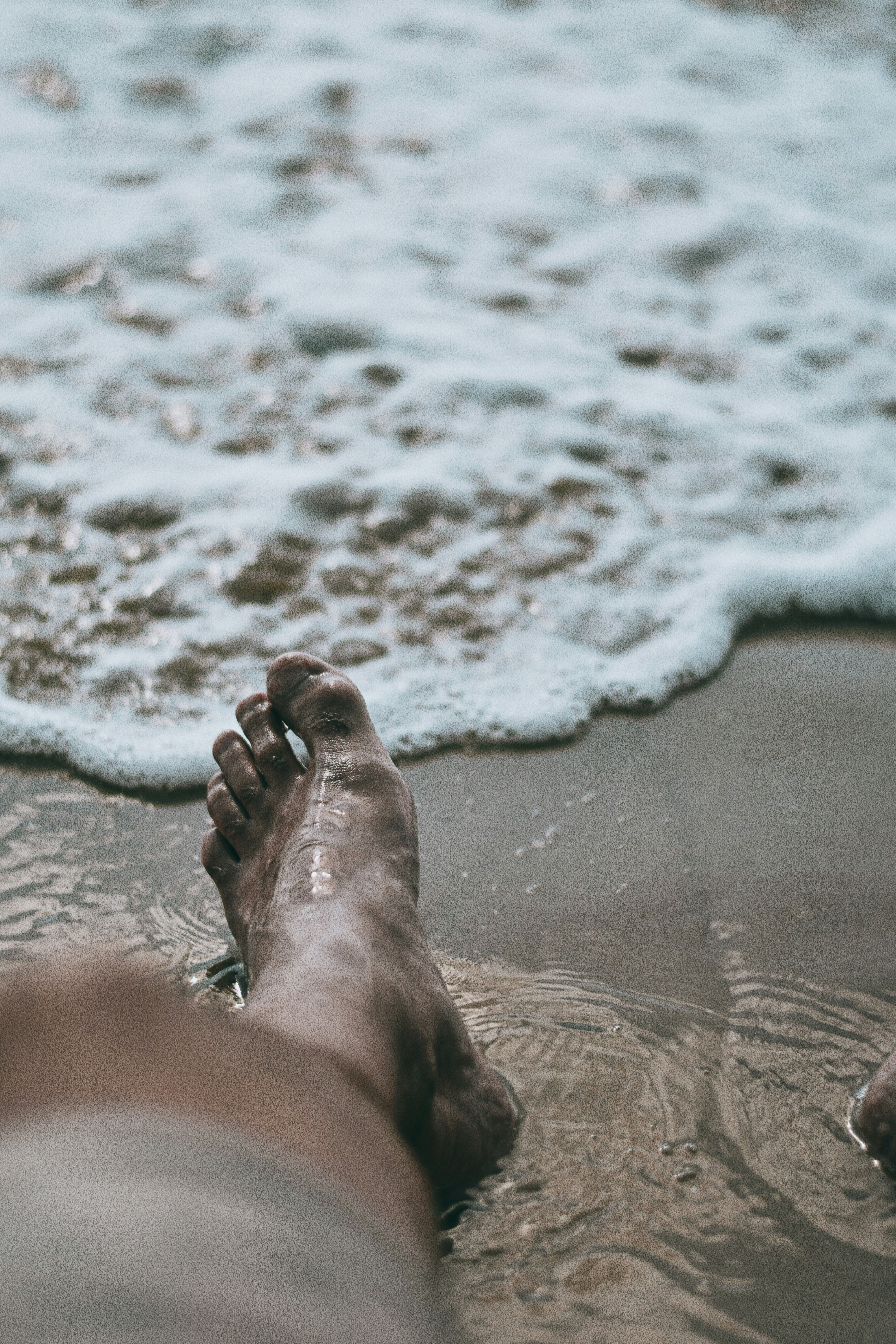 persons feet on beach during daytime