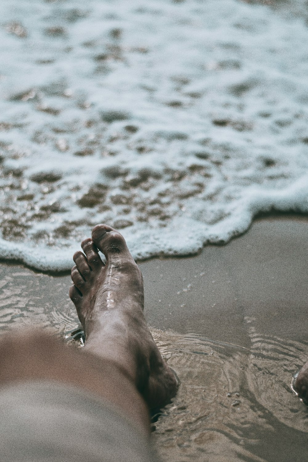 persons feet on beach during daytime
