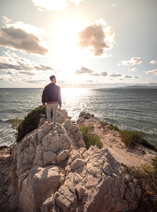 man in black shirt standing on rock formation near sea during daytime in Salou Spain