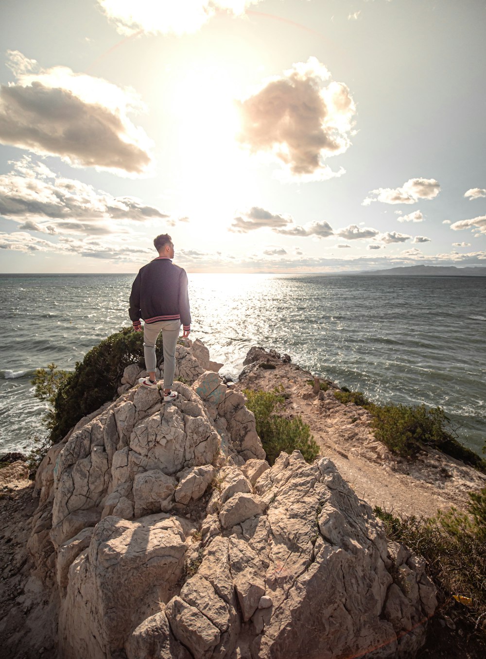 man in black shirt standing on rock formation near sea during daytime