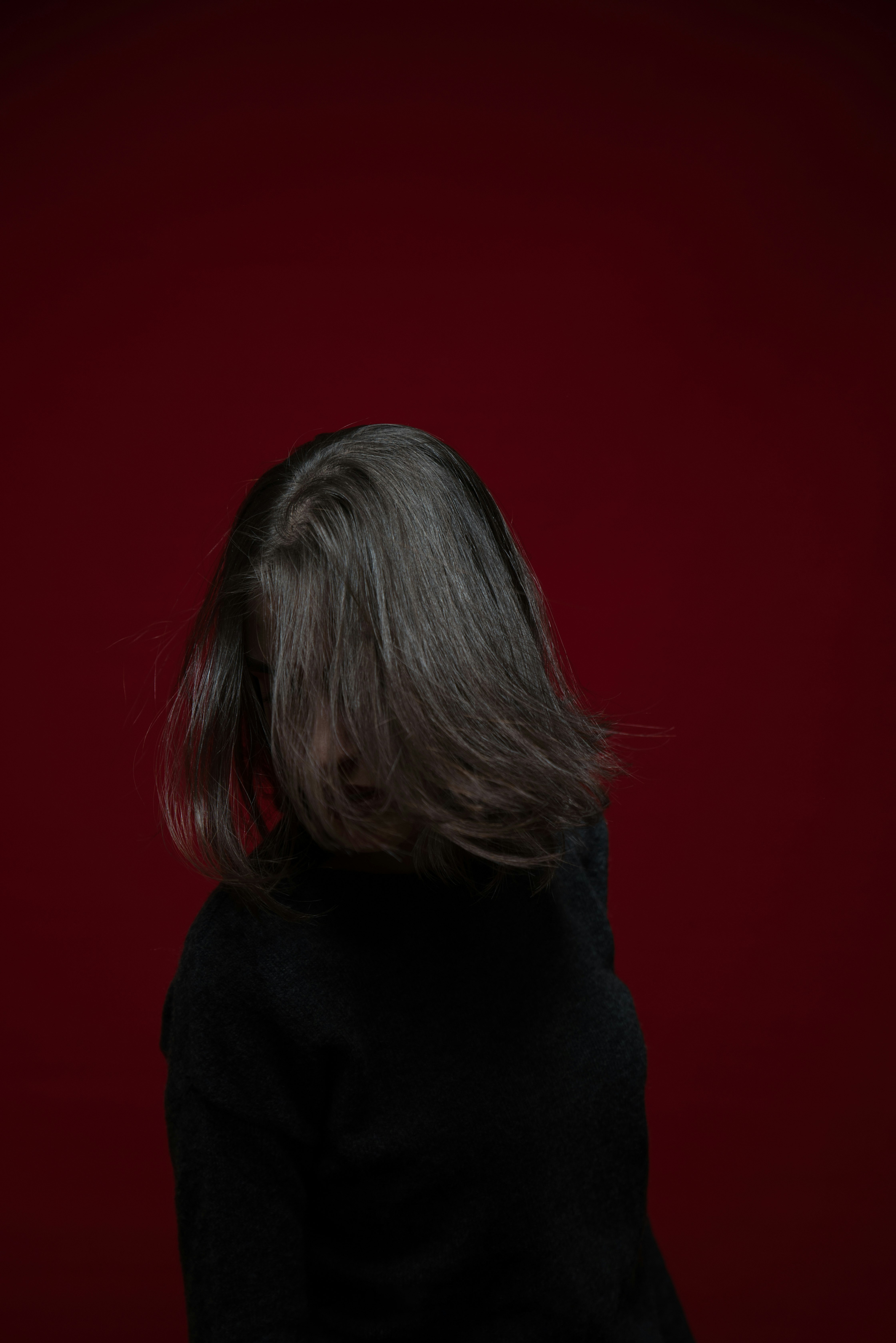 woman in black hoodie standing near red wall