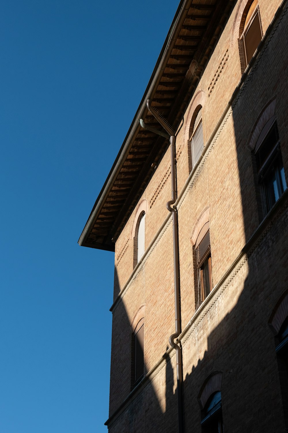 a tall brick building with windows and a sky background