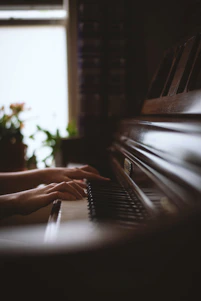 A warm, inviting piano classroom filled with students playing and a teacher guiding them with a smile.