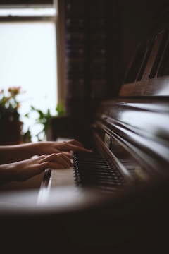 Hands playing piano keys with soft natural lighting.