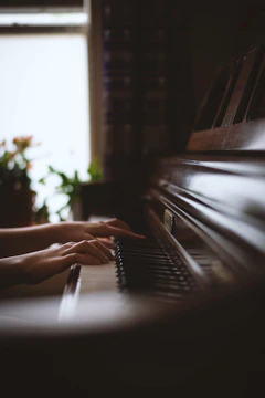 Close-up of hands playing a keyboard with soft lighting creating a serene atmosphere.