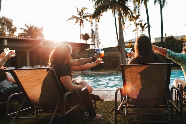A group of friends relaxing by a sparkling outdoor pool at sunset.