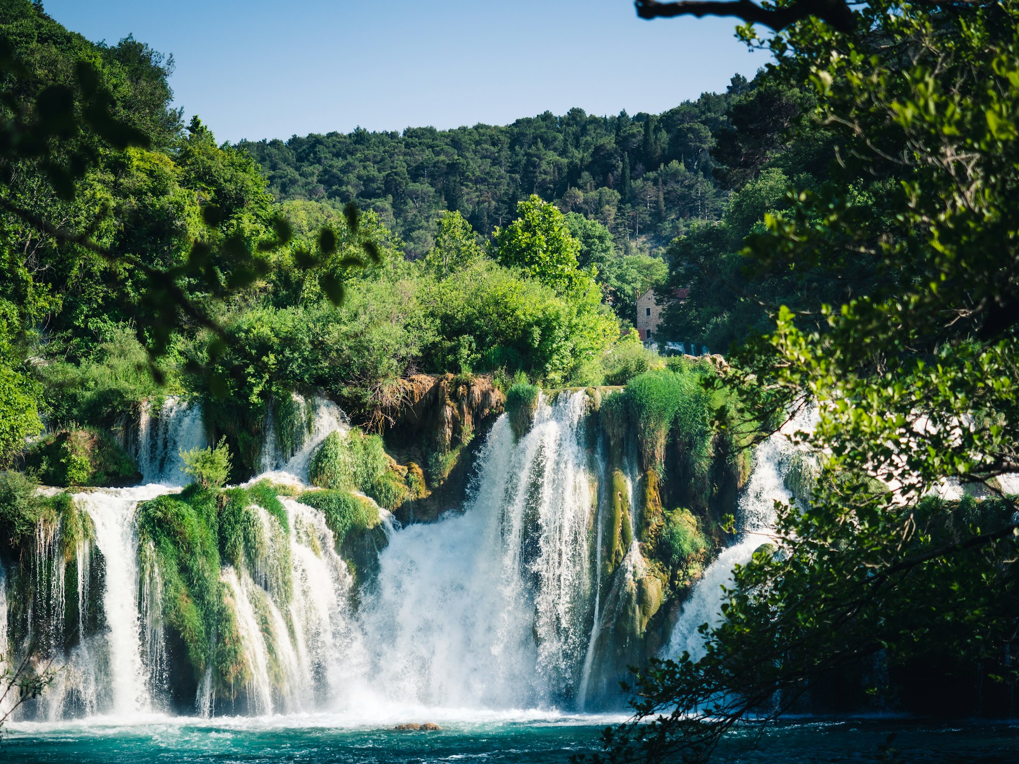 Majestic waterfalls in the Krka national park. White water crashing down into a basin of water, surrounded by a lush green vegetation. 