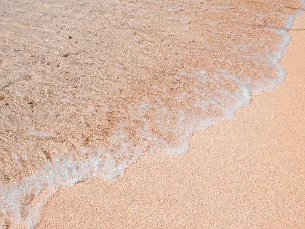 arena marrón cerca del cuerpo de agua durante el día