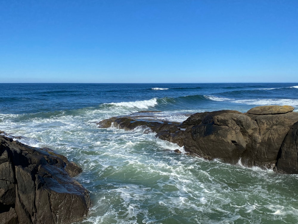 brown rock formation near sea under blue sky during daytime