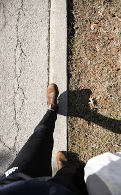 a person standing on a sidewalk with their feet on the ground