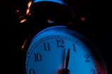 Close-up of a sleek red LED digital alarm clock glowing softly in a dark room.