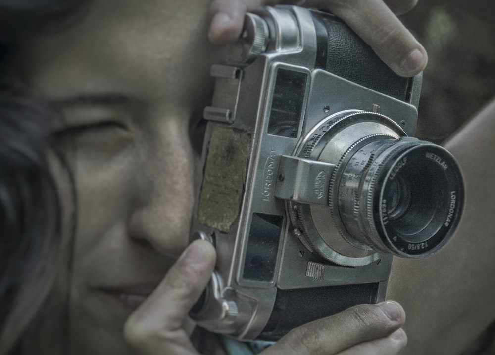 person holding black and silver camera