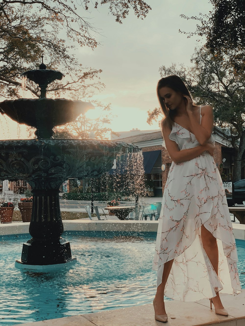woman in white sleeveless dress standing near water fountain during daytime