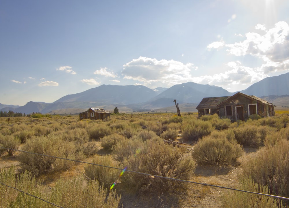 brown wooden house near green grass field under white clouds and blue sky during daytime