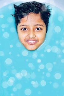 A cheerful toddler blowing bubbles in the water during a playful lesson