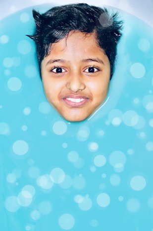 A joyful moment of a child blowing bubbles underwater with the help of their teacher.