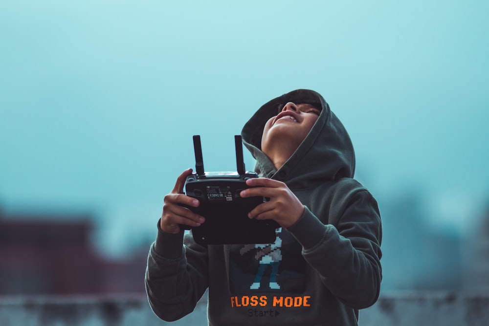 woman in black hoodie holding black dslr camera