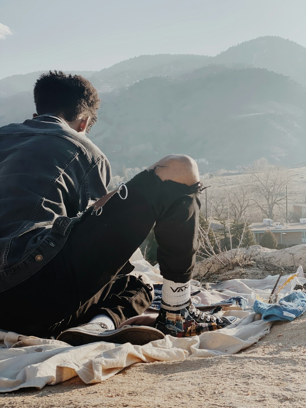 man in black jacket sitting on brown rock during daytime