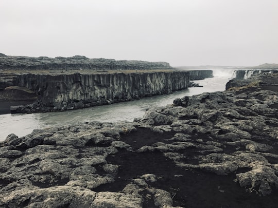 gray rocky shore near body of water during daytime in Dettifoss Iceland