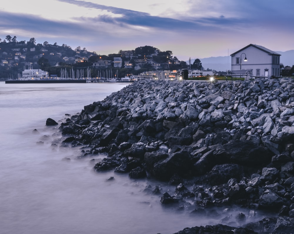 white and brown house on black rock formation near body of water during daytime