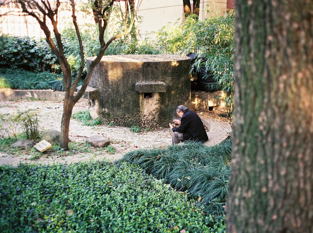 man in black jacket sitting on green grass during daytime