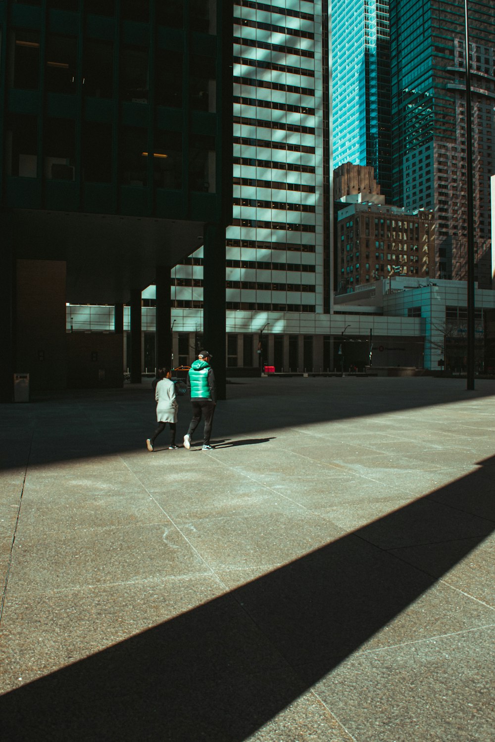 man in blue jacket and black pants walking on sidewalk during daytime